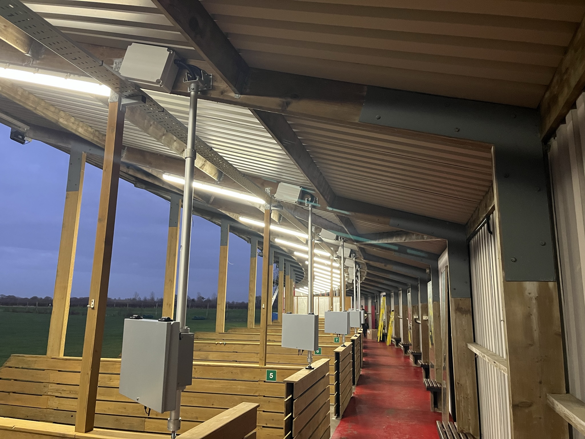 Electrical infrastructure and equipment enclosures across driving range bays